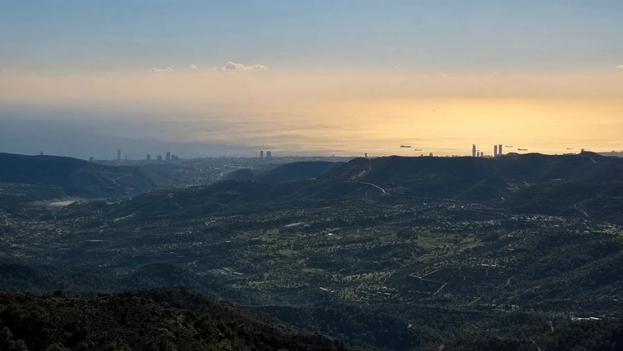 View across wooded hills towards the coast from Kakomallis at sunset