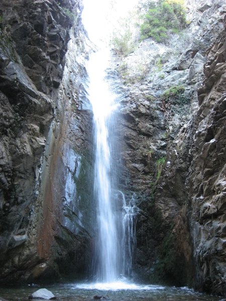 Tall Millomeris waterfall plunging down a shaded rock face