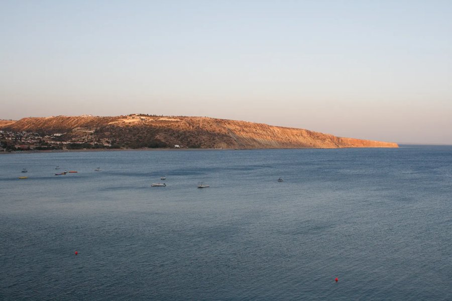 Pissouri Bay and the Cape Aspro headland at golden hour with boats