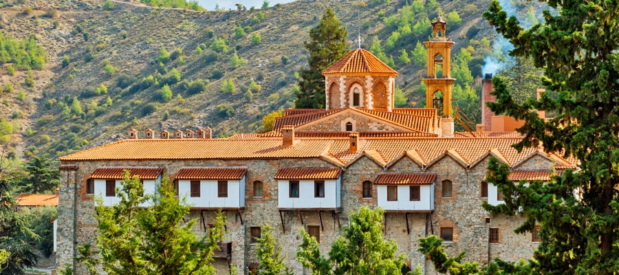 Machairas Monastery against a wooded mountain slope